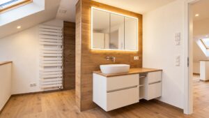 Saniertes Badezimmer mit Holzwaschtisch und beleuchtetem Spiegel